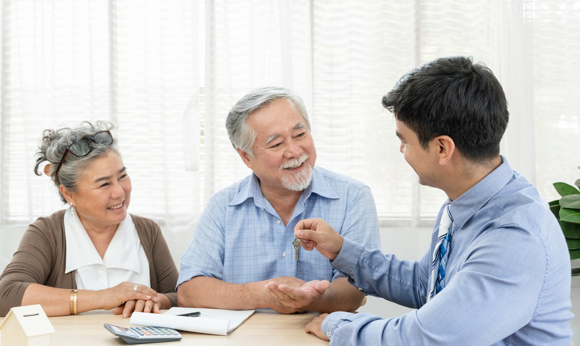 A smiling older couple sitting at a table across from a financial planner.