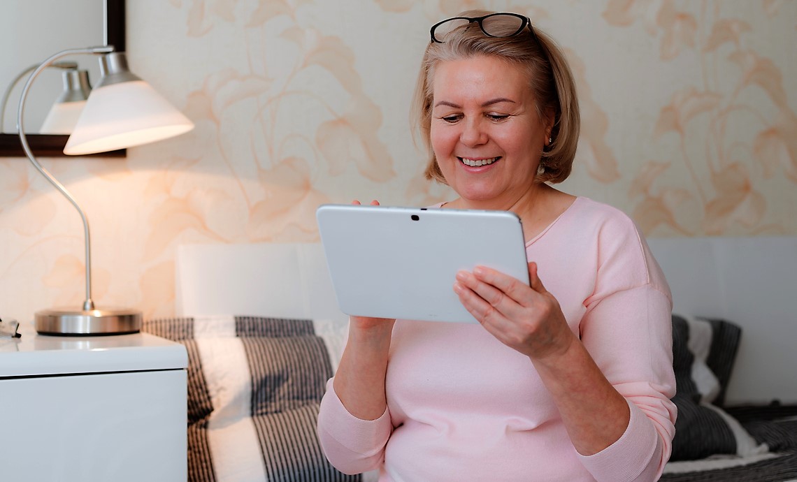 Older woman in bedroom reading RTOERO white paper on tablet