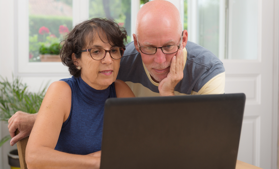 White couple using a laptop to learn more about racism and oppression in their community.